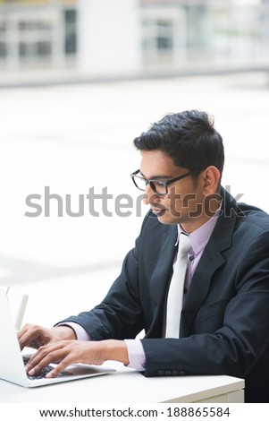 young indian business man on laptop and coffee at a cafe, focus on computer