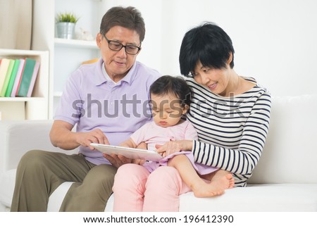 asian grand parents teaching grand son with tablet