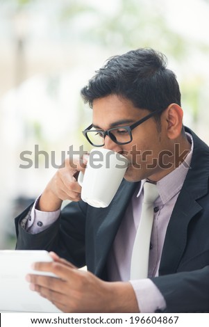 young indian business man with a tablet computer and coffee at a cafe