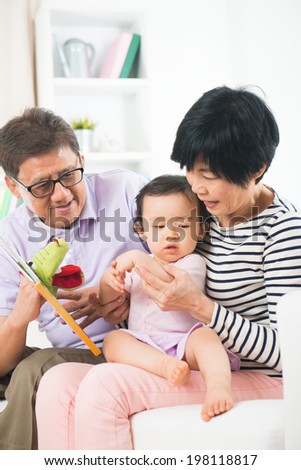 chinese grandparents reading story book to grand daughter