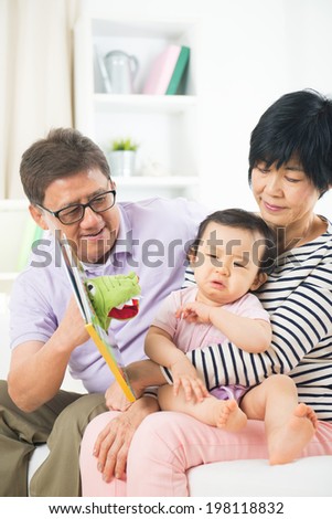 chinese grandparents reading story book to crying grand daughter