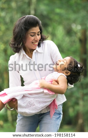 indian mother carrying daughter playing in outdoor park