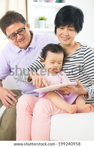 asian grand parents teaching grand son internet with a tablet