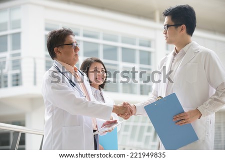 Asian medical team of doctors shaking hands inside hospital building