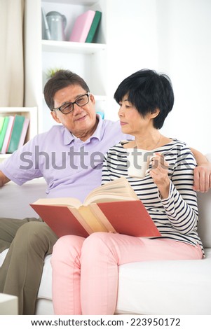 asian senior couple reading book and writing with coffee or tea