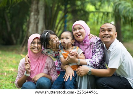 malay muslim family having fun playing in the park
