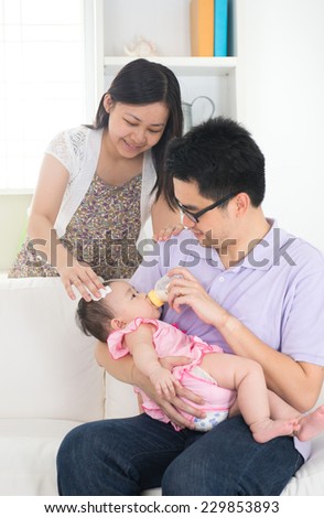asian parents bottle feeding their baby
