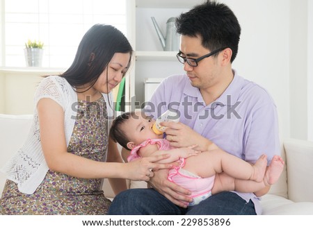 asian parents bottle feeding their baby