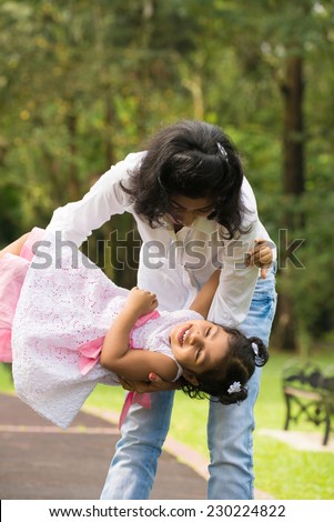Happy Indian mother and daughter playing in the park. Lifestyle image.