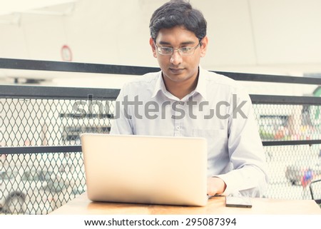 Asian Indian businessman sitting on chair and using laptop while waiting his flight at airport.