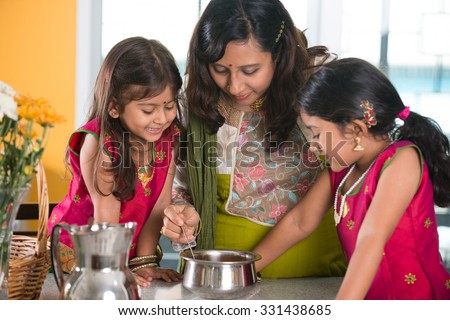 indian mother cooking with her daughters at kitchen