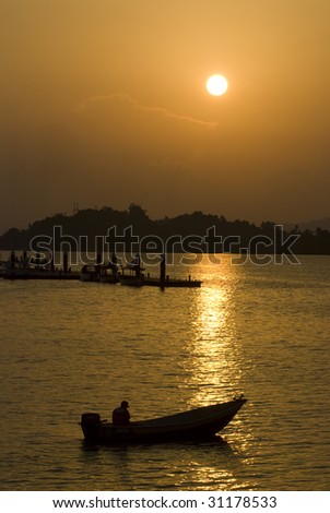 silhouette of an angler on a boat during sunset