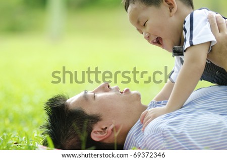 asian dad playing with son on green outdoor