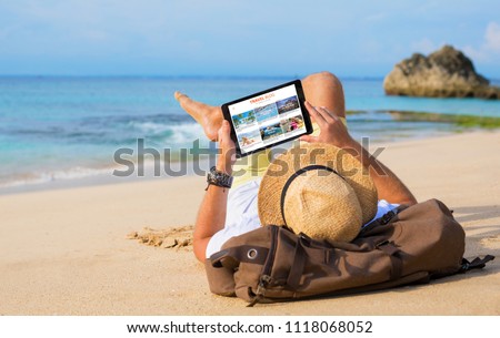 Man reading travel blog on beach