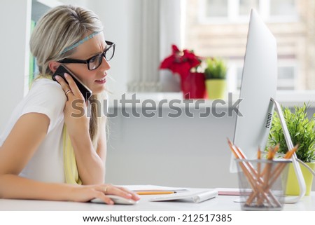 Young creative woman talking on phone in the office