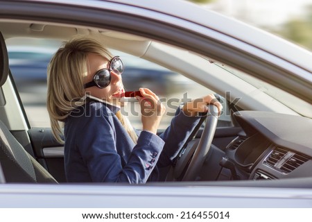 Busy woman manage to talk on phone and do makeup while driving a car
