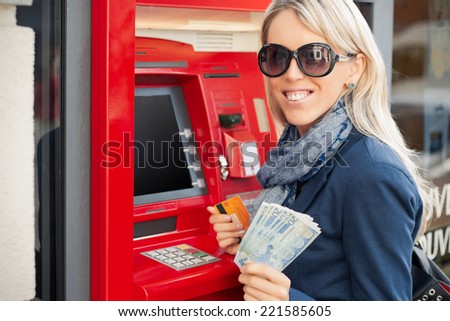 Beautiful young woman showing cash after withdrawal from ATM