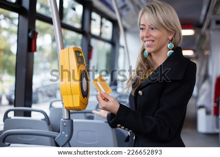 Woman using electronic ticket punching machine in public transport