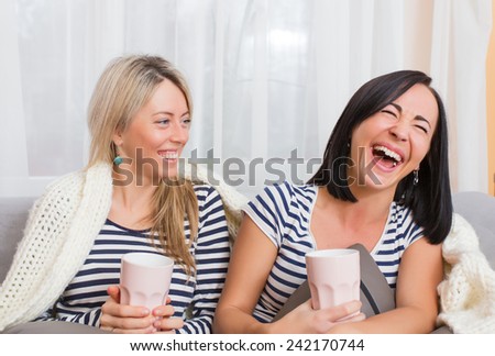 Two cheerful women laughing while sitting comfortably in bed