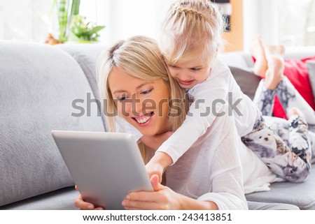 Little girl with her mother using tablet computer