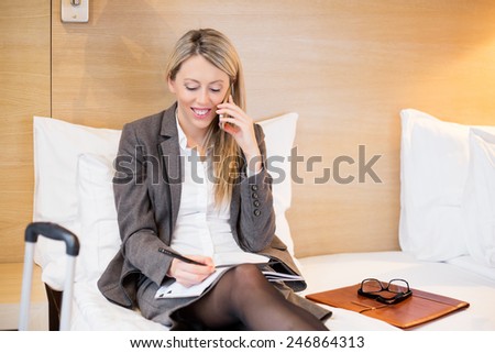 Business woman in hotel room talking on phone while on business travel