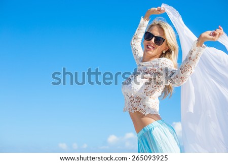 Happy woman holding white fabric on bright summer day with clear blue sky background