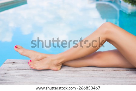 Beautiful slim women legs by the swimming pool