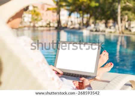 Woman using laptop computer by the pool Woman using laptop computer by the pool