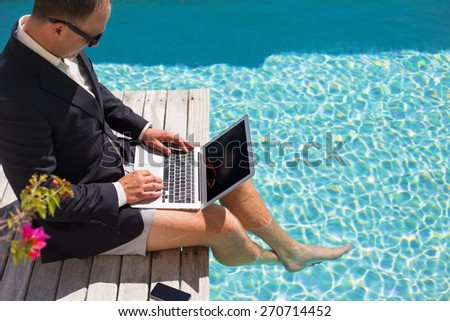 Businessman working with laptop computer by the pool