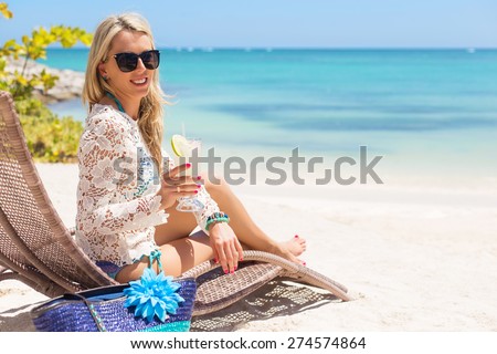 Woman drinking cocktail and relaxing in chair on the beach
