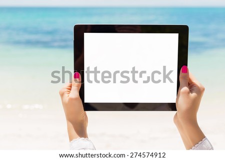 Woman holding tablet computer with empty screen on the beach