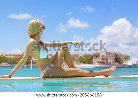 Woman relaxing and looking into distance by the pool