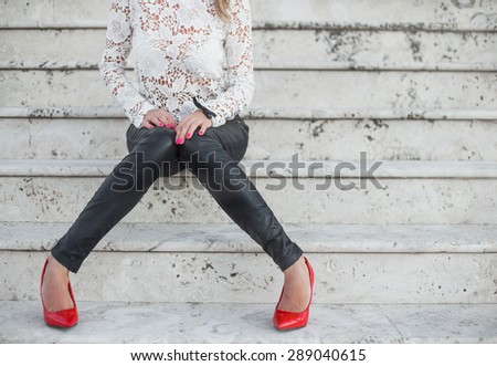 Sexy lady in red high heel shoes sitting on stairs