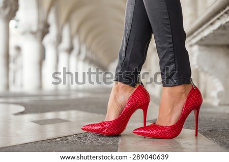 Woman in black leather pants and red high heel shoes