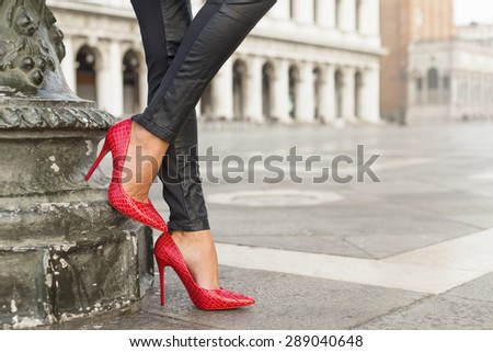 Woman in black leather pants and red high heel shoes
