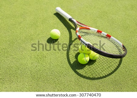Tennis racket and balls on the court grass
