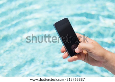 Mobile phone in hand by the pool