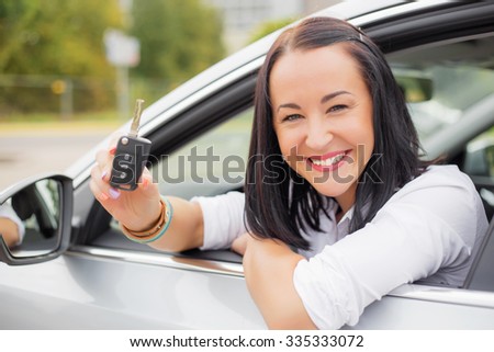 Woman driver leaning out the car window with keys in her hands