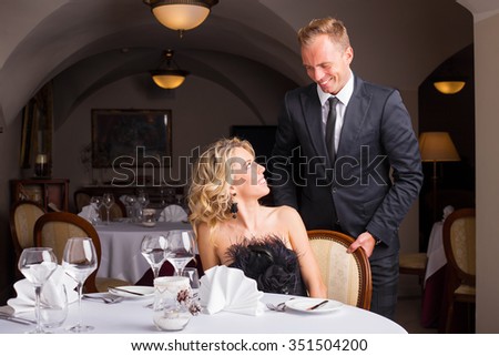 Man being a gentleman and helping woman with her chair