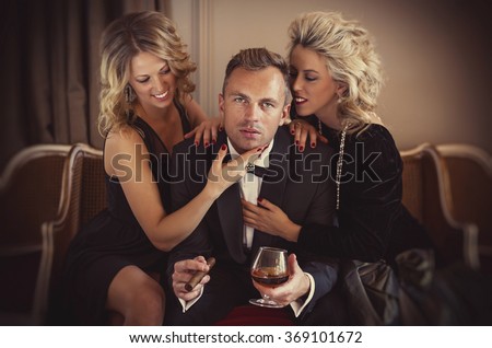 Man being adored by two glamorous women