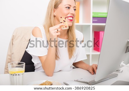 Woman having granola bar while working