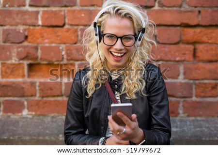 Happy woman with headphones listening to music on her smartphone