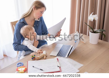 Working mom talking on the phone with child in her lap