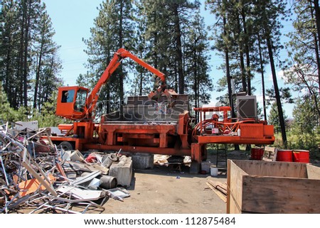 A large orange compacting machine turns loose aluminum cans into large bricks to be melted down and reused.