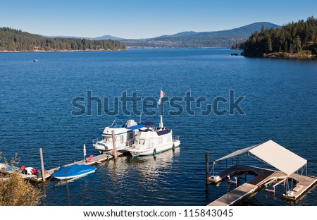 Boats tied to a floating dock on a deep blue lake surrounded my mountains on an early fall day.