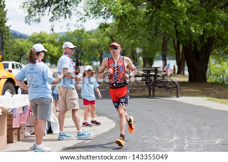 COEUR D ALENE, ID - JUNE 23: Ben Hoffman from CO runs past event volunteers at the June 23, 2013 Ironman Triathlon in Coeur d\'Alene, Idaho. Ben won the Coeur d\'Alene Ironman with a time of 8:17:31.