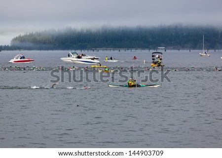 COEUR D ALENE, ID - JUNE 23:   A line of swimmers in the water between event staff on a foggy morning at the June 23, 2013 Ironman Triathlon in Coeur d'Alene, Idaho.