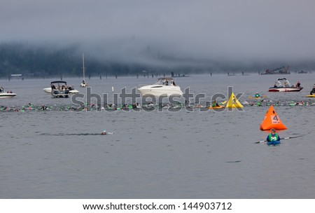 COEUR D ALENE, ID - JUNE 23:   A line of swimmers in the water between event staff on a foggy morning at the June 23, 2013 Ironman Triathlon in Coeur d\'Alene, Idaho.
