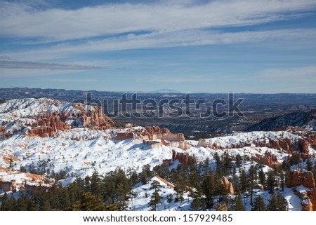 Bryce Canyon National Park in Utah on a sunny winter day showing colorful canyon formations lightly covered in snow.
