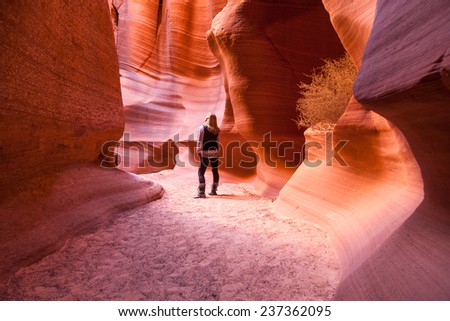 A woman stands among the ancient sandstone walls of Canyon X and admires the work of nature.